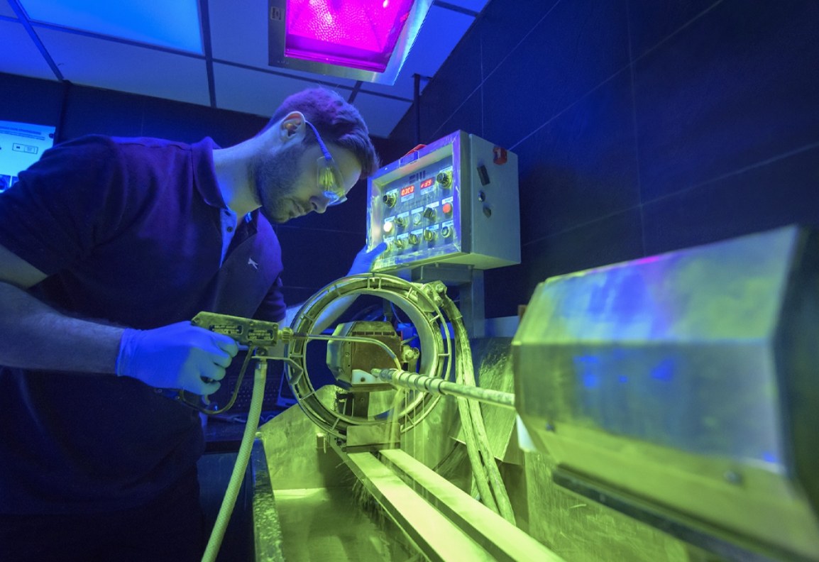 A technician carrying out magnetic particle inspection on an aerospace component under ultraviolet light