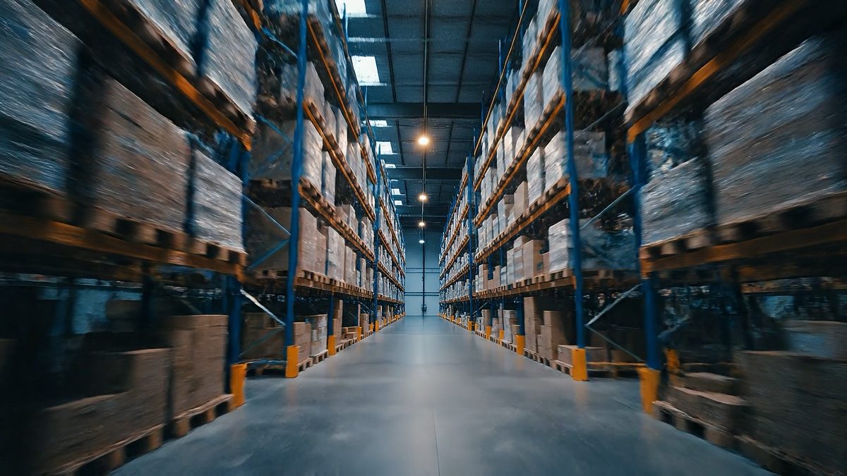 Long aisle of pallet racking stocked with wrapped goods in a distribution warehouse
